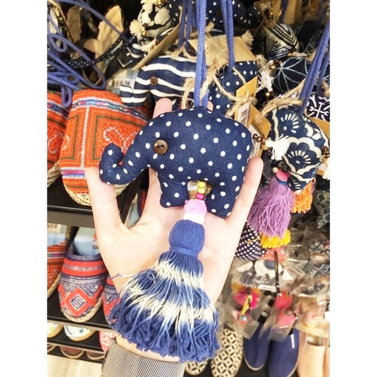 Embroidery Handmade Elephant Keychain with indigo-dyed bottom tassel. Elephant body size 7 cm. Has a bell on the elephant's tail. Elephant holds up its trunk and hangs on a bag. Cute. Handmade. Souvenir from Chiang Mai.